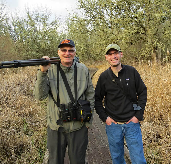 Two men in fields, one carrying a camera